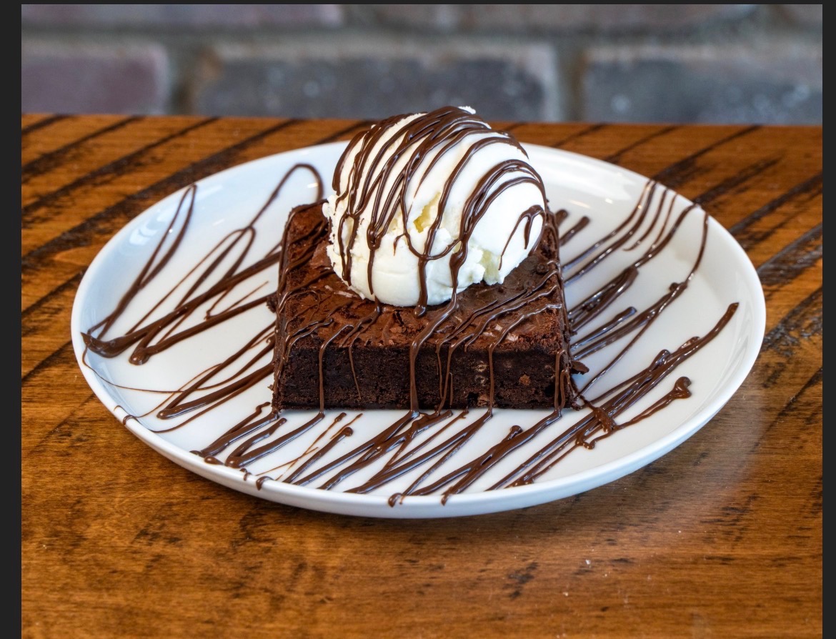 Warm brownie topped with vanilla ice cream and chocolate drizzle