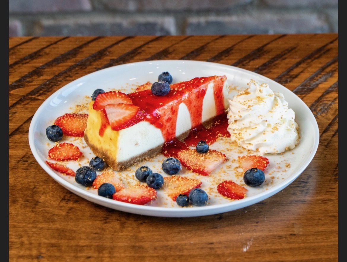 New York cheesecake slice topped with strawberry compote and fresh berries