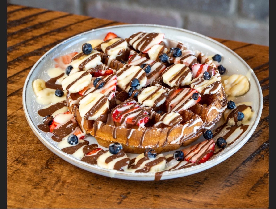Waffle loaded with banana, strawberry, blueberry and milk and white chocolate drizzle