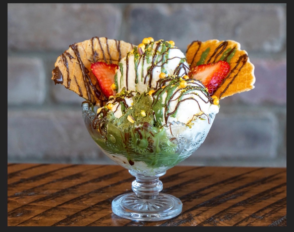 Pistachio and vanilla ice cream sundae with wafers and fresh strawberries
