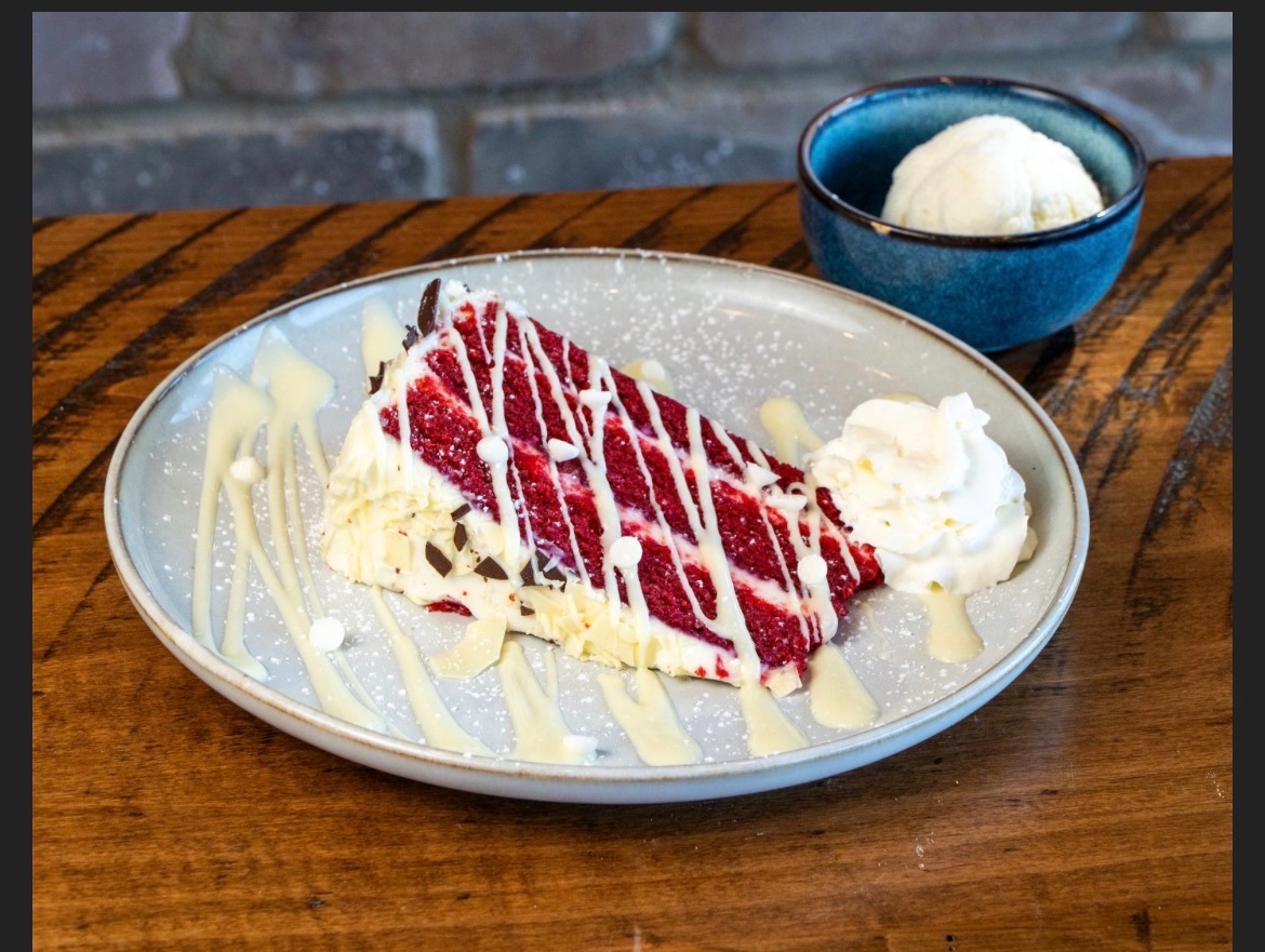 Red velvet cake slice served with a cup of vanilla ice cream